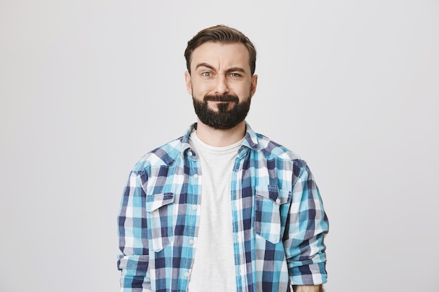 Puzzled bearded funny guy making confused face