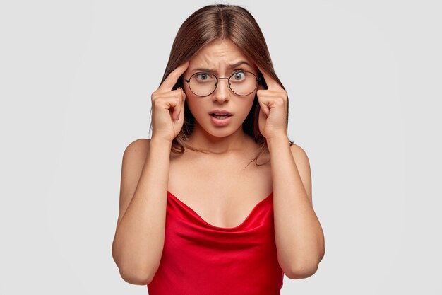 puzzled brunette young woman posing against the white wall