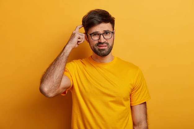 Puzzled indecisive man scratches head, has no idea