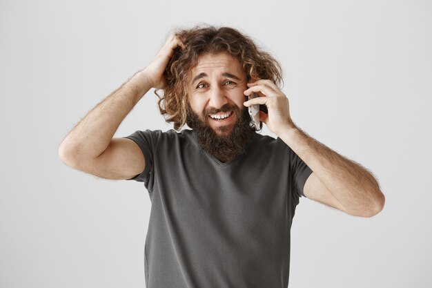 Puzzled indecisive middle-eastern talking on phone and scratching head confused