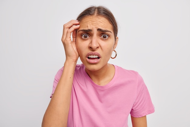 Foto gratuita perplesso di indignato giovane donna loos infastidito dalla telecamera fissa dispiaciuto reagisce su qualcosa di spiacevole indossa maglietta casual isolata sul muro bianco