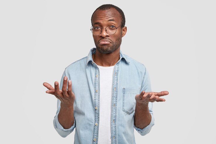 Puzzled man look with clueless expression, looks doubtfully, can`t make decision, dressed in casual clothes, isolated over white wall