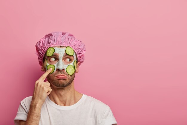 Puzzled man points at face, looks aside, claims on having blackheads