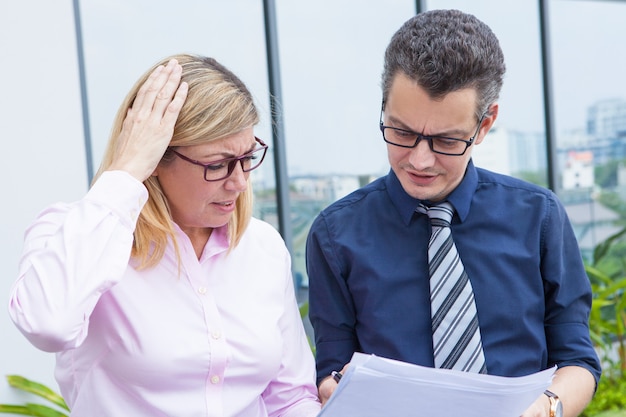 Free photo puzzled mature businesswoman displeased with report data while discussing it