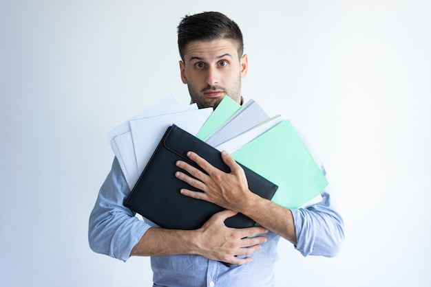 Puzzled office worker holding pile of documents