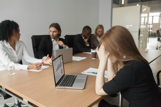 Puzzled serious businesswoman concerned about project statistics at group meeting