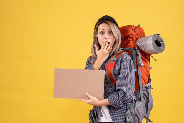 puzzled traveler woman with backpack holding cardboard