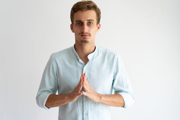 Puzzled upset guy in white casual shirt praying or asking for help.