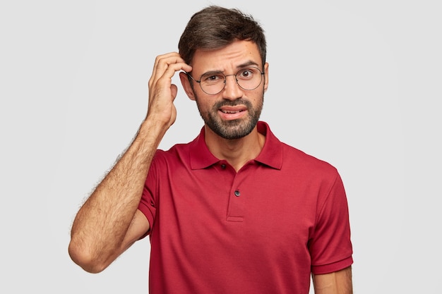 Puzzled young emotional man posing against the white wall