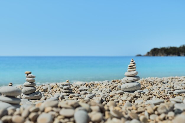 Pyramid stones balance on the beach against the background of the sea and the sky Object in focus blurred background idea of a vacation or retweet by the sea