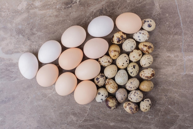 Quail and chicken eggs isolated on marble table.