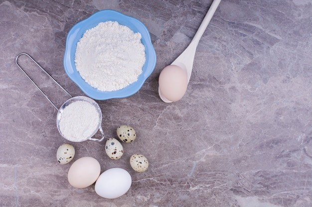 Quail and chicken eggs with a cup of flour.