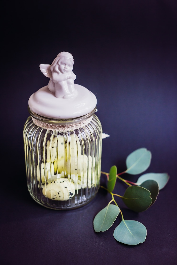 Free Photo quail eggs in glass bottle with porcelain angel on it