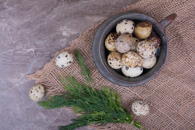 Quail eggs and herbs in a wooden cup.