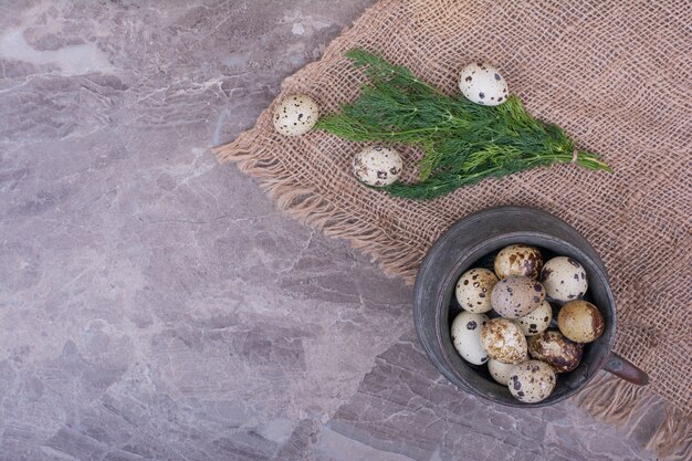 Quail eggs in a metallic pot on the burlap