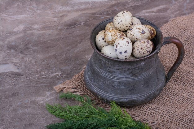 Quail eggs in a metallic pot with herbs