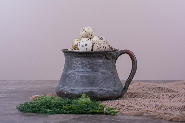 Quail eggs with herbs in a metallic cup.