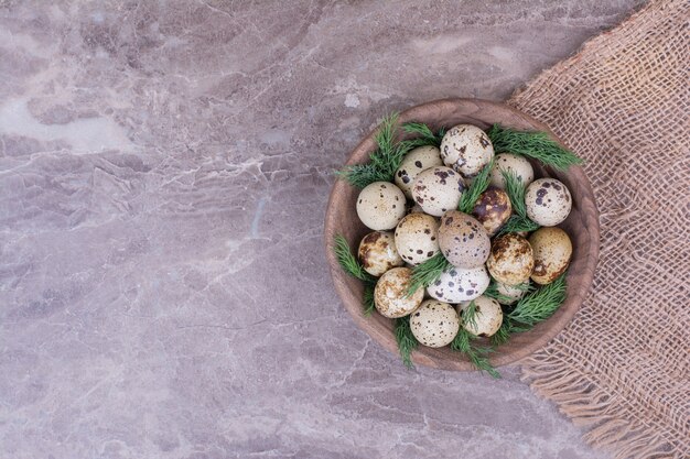 Quail eggs with herbs in a wooden cup.