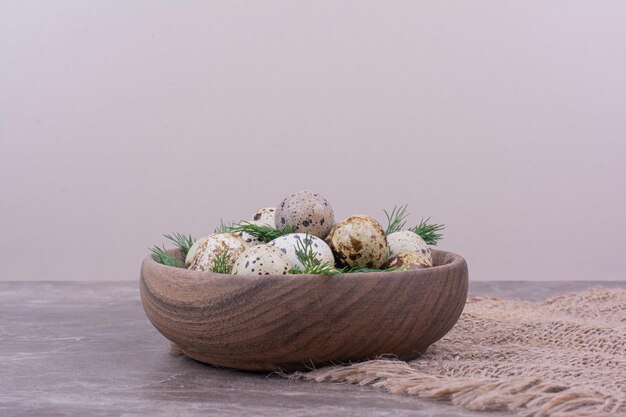 Quail eggs with herbs in a wooden cup.