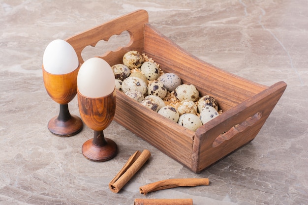 Quail eggs in a wooden tray on stone surface