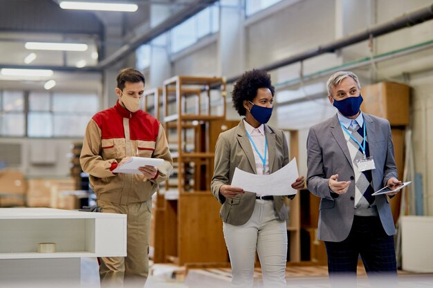 Quality control inspectors communicating while walking through woodworking facility during coronavirus pandemic