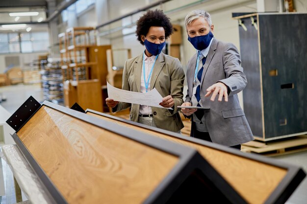 Инспекторы по контролю качества в масках контролируют обработку древесины на производственном предприятии