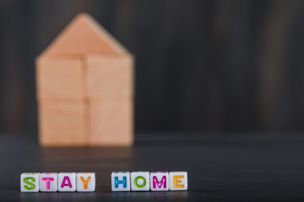 Quarantine at home concept with wooden home, white cubes grey.