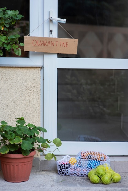 Знак карантина на входной двери с продуктами