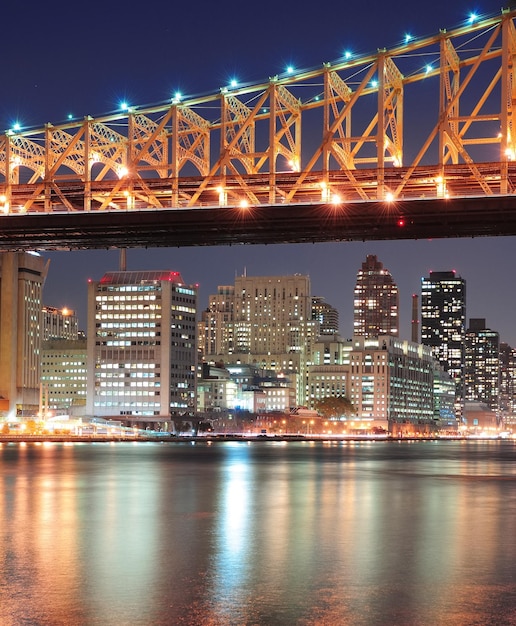 Foto gratuita queensboro bridge sopra new york city east river al tramonto con riflessi sul fiume e skyline di midtown manhattan illuminato.