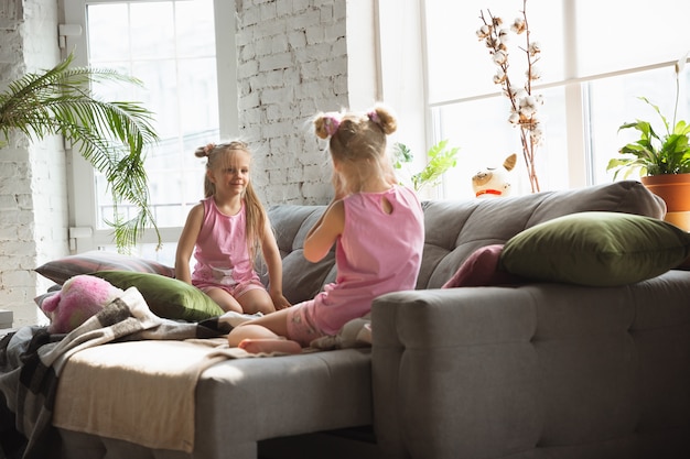 Quiet little girls waking up in a bedroom in cute pajamas, home style and comfort