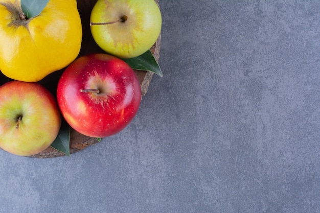 Free photo quince and apples on board on the dark surface