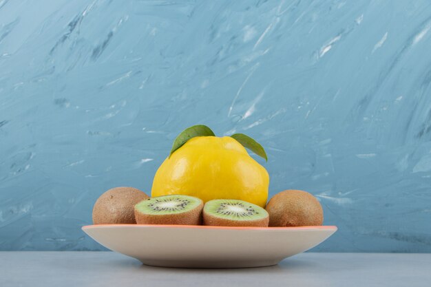 Quince and sliced kiwis on orange plate. 