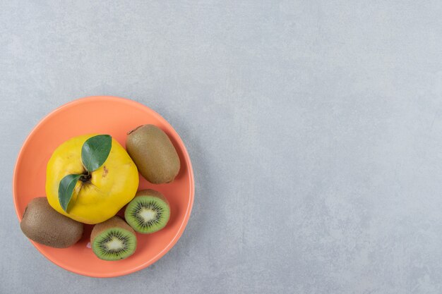 Quince and sliced kiwis on orange plate. 