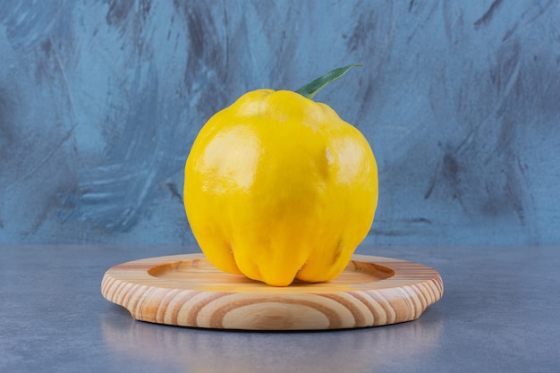 Free photo quince on a wooden plate on the dark surface