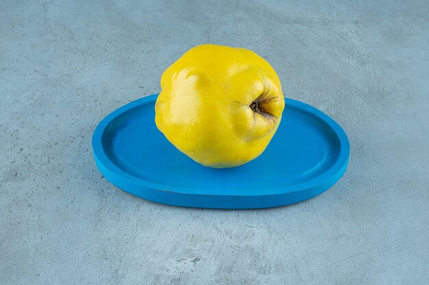 Quince on a wooden plate , on the marble table. 