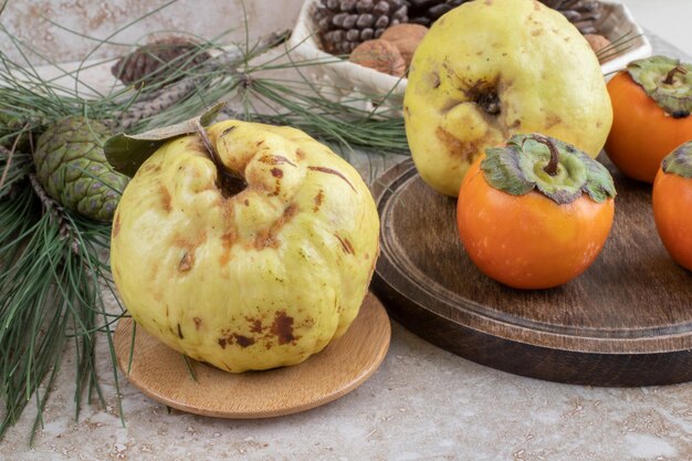 Quinces and oriental persimmons in a decorative arrangement on marble surface.