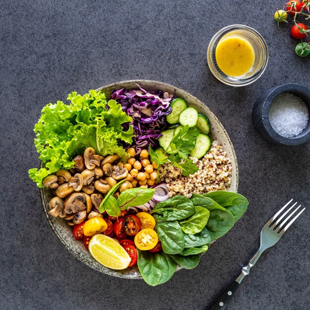 Quinoa, mushrooms, lettuce, red cabbage, spinach, cucumbers, tomatoes in a Buddha bowl