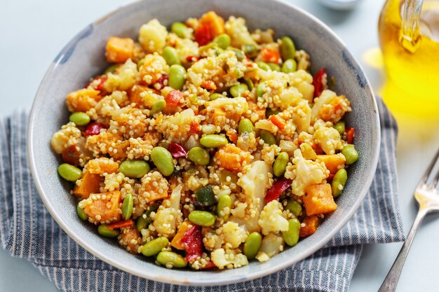 Quinoa with vegetables cooked for lunch or dinner and served in bowl. Closeup.