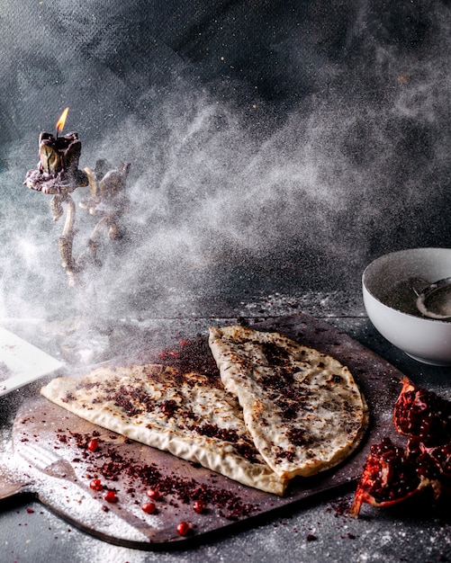 Qutabs delicious meat and pumpkin dish poured up wth flour with pomegranate slices and sumax on the grey surface