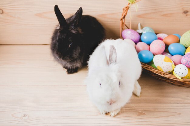 Rabbits near basket with eggs