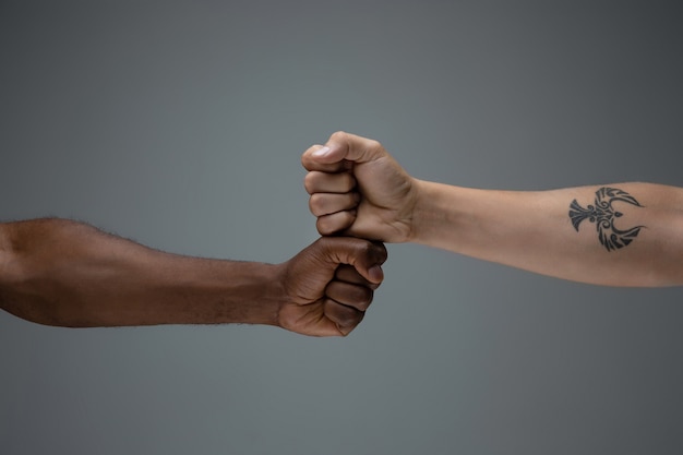Racial tolerance. Respect social unity. African and caucasian hands gesturing isolated on gray
