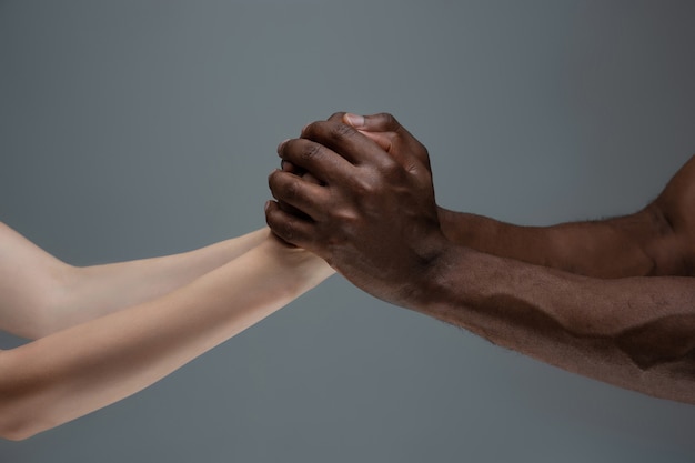 Racial tolerance. Respect social unity. African and caucasian hands gesturing isolated on gray