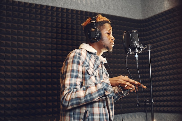 라디오 스튜디오에서 팟 캐스트를 녹음하는 동안 몸짓을하는 라디오 호스트. 아프리카 남자는 녹음 스튜디오에서 리허설.