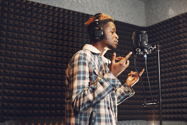 Free photo radio host gesturing while recording podcast in radio studio. african man rehearses in a recording studio.