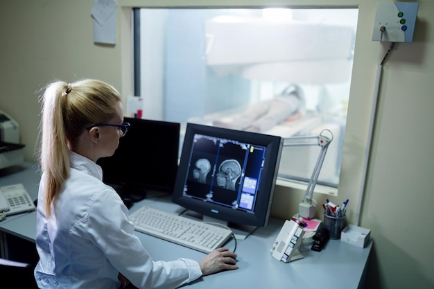 Radiologist analyzing brain MRI scan results of a patient on computer monitor in control room