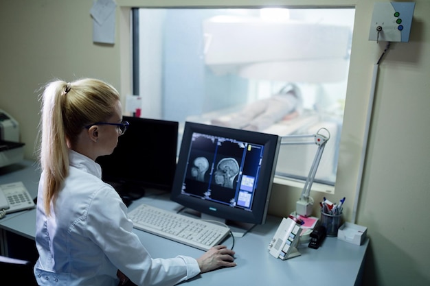 제어실의 컴퓨터 모니터에서 환자의 뇌 MRI 스캔 결과를 분석하는 방사선 전문의