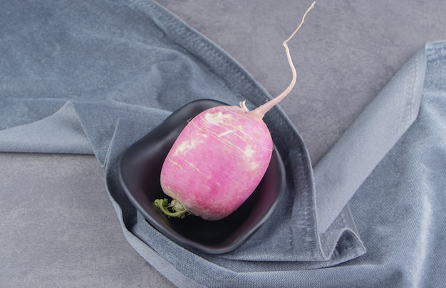 Radish in a bowl on the towel on the marble surface