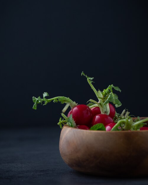 Radish plant on wooden bowl