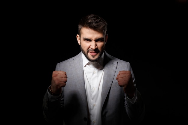 Rage young successful businessman angering over black wall