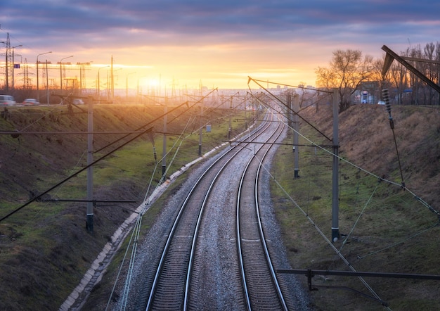 Railroad at sunset. fantastic industrial landscape with railway station, trees, grass and blue cloudy sky and bright orange sunlight. railway junction. heavy industry in the city. cargo shipping